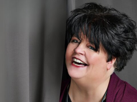 Ingrid Kühne lachend vor Vorhang