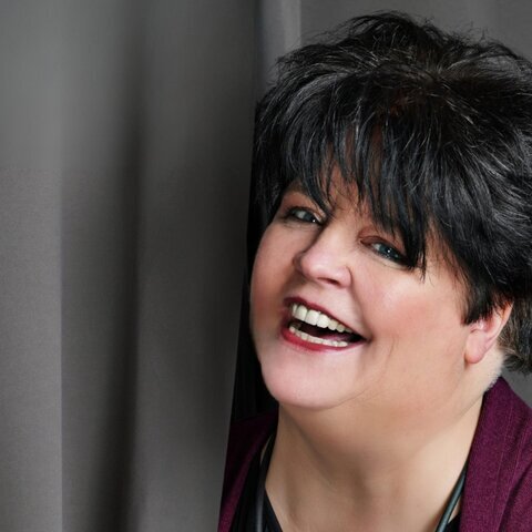 Ingrid Kühne lachend vor Vorhang