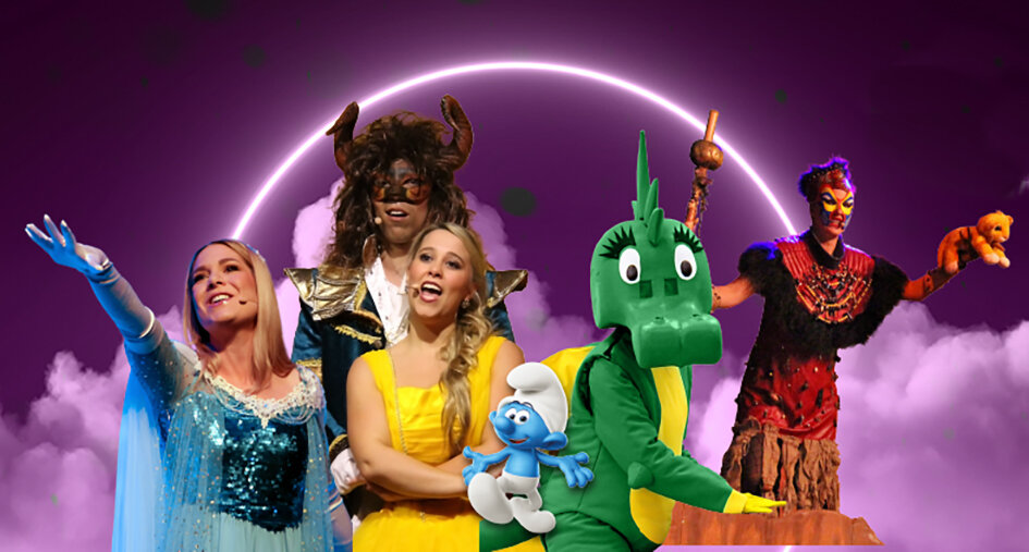 Bunte Bühnenaufnahme eines Familienmusicals mit mehreren kostümierten Darstellerinnen und Darstellern: eine Frau im glitzernden blauen Kleid, eine Sängerin im gelben Kleid, eine tierische Fantasiefigur mit Hörnern, ein grünes Drachenkostüm, eine kleine blaue Zeichentrickfigur sowie weitere märchenhafte Charaktere vor violett leuchtendem Hintergrund.